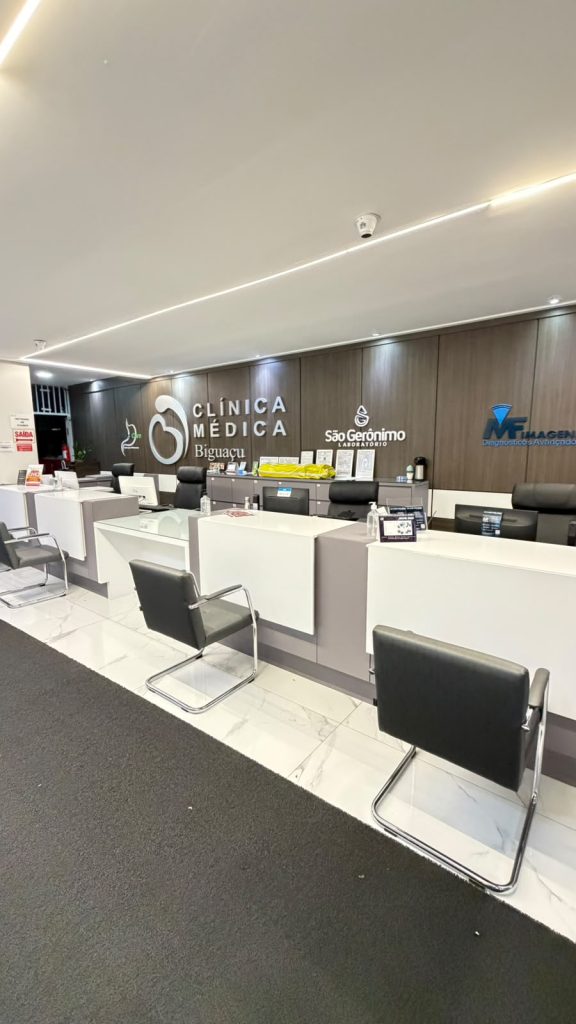 Balcão de recepção da Clínica Médica Biguaçu com painel institucional